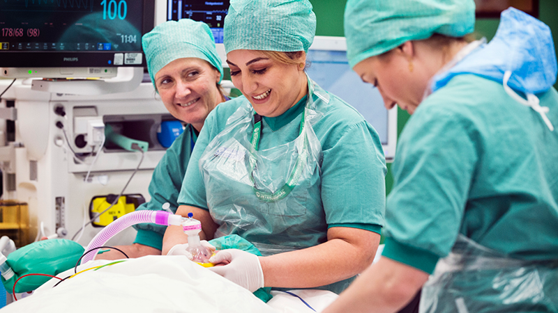 Bild som visar tre vårdpersonal i ett operationsrum.