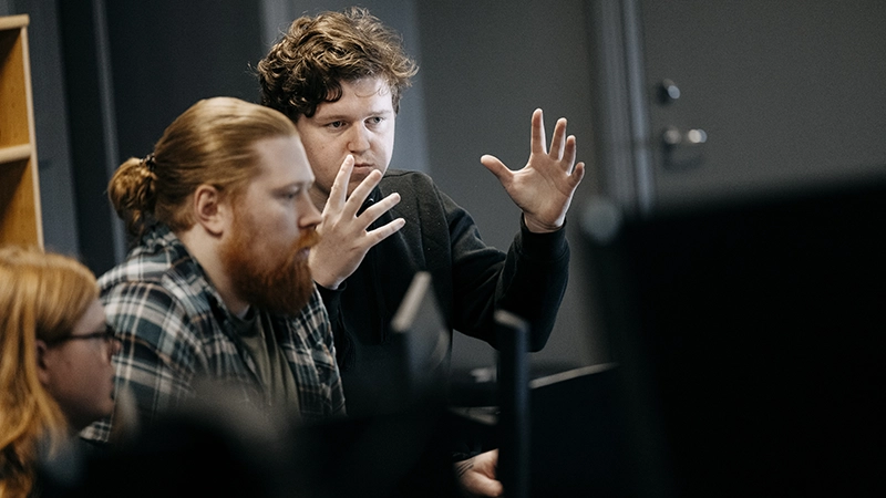 Kille gestikulerar framför en dator. 