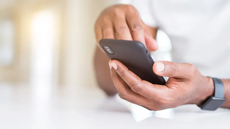 närbild på händer som håller i och skriver på en mobiltelefon