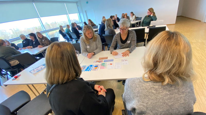 personer sitter runt bord i konferensrum och samtalar