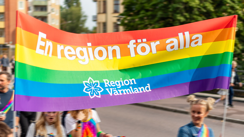 Regnbågsfärgad banderoll med texten: En region för alla. 