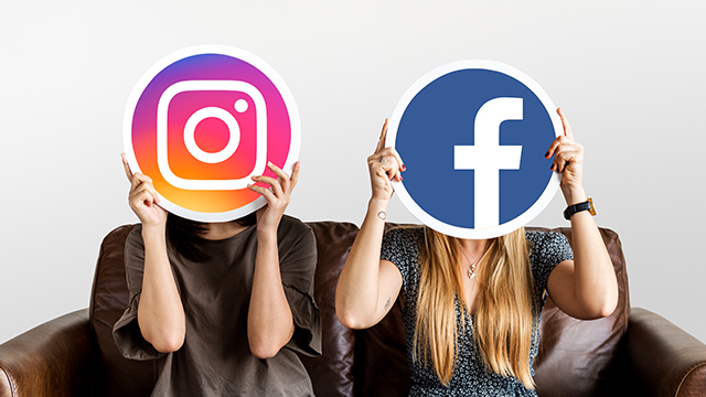 Två personer i en soffa. En håller en Instagram-skylt för ansiktet, den andra en Facebook-skylt.