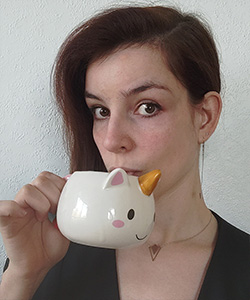 Porträttbild av Claire Denaux som håller upp en enhörningskopp. 
