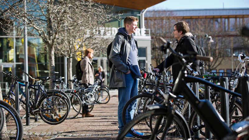 Två studenter som står vid cykelparkeringen utanför Karlstads universitet