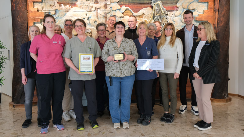 Ett stort antal medarbetare i en gruppbild. De visar upp ett diplom och en stor check.