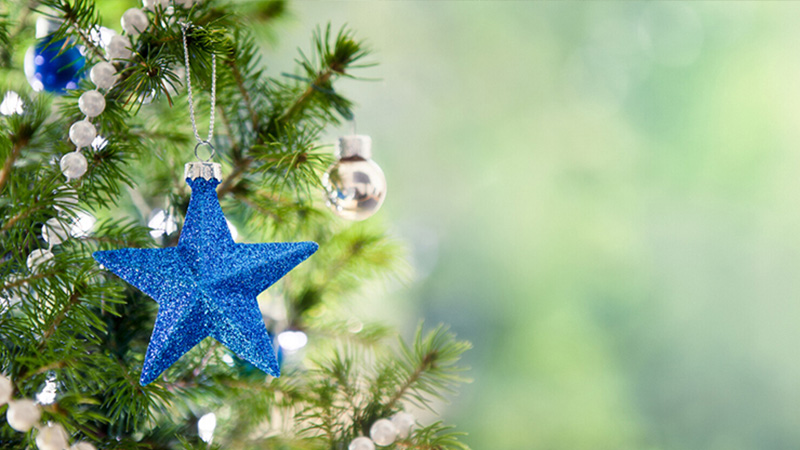 En blå stjärna hänger som dekoration i en julgran. 