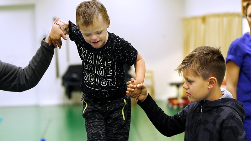 En liten kille får hjälp av en lite äldre kille att balansera. 