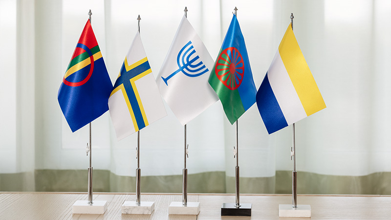 Färgglada flaggor med symboler står på rad på ett bord.