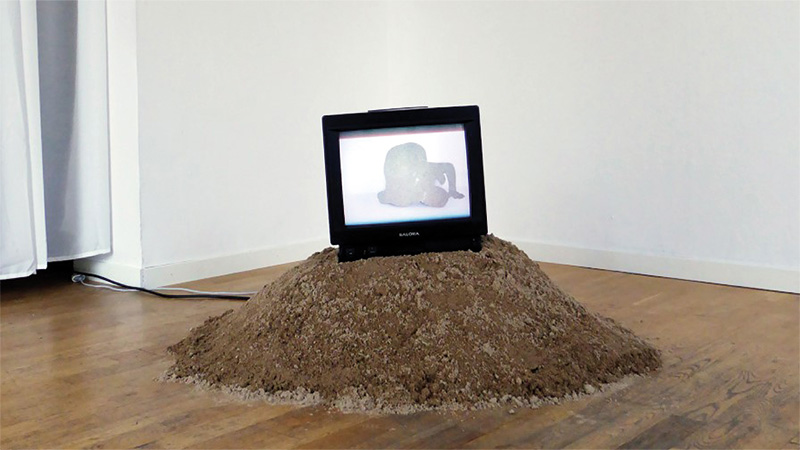 En jordhög på ett golv med en dator på toppen. 
