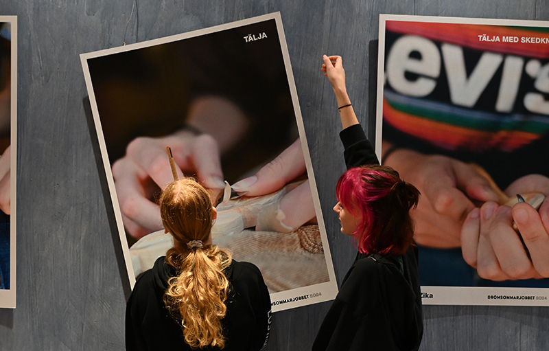 Två personer hänger en utställning med fotografier i A2 format