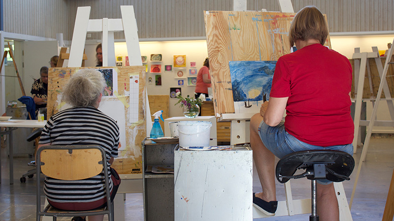 Två personer sitter och målar vid varsitt staffli. 