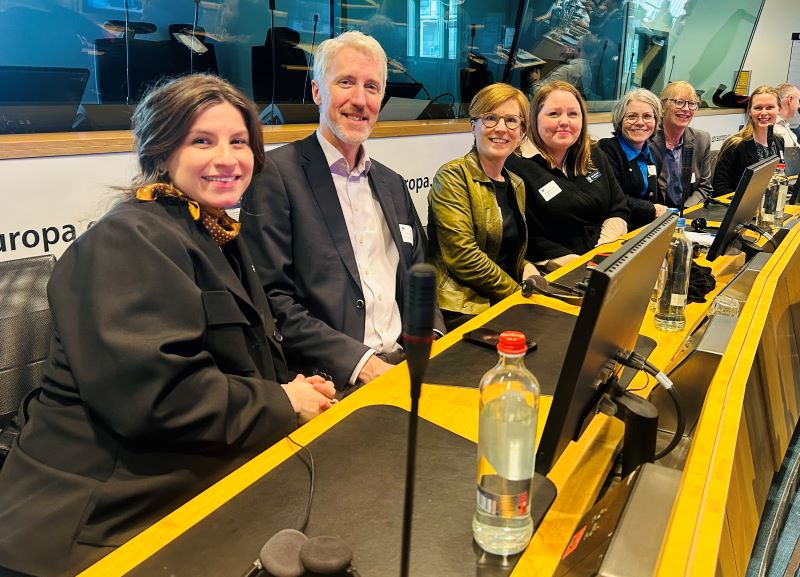 Flera människor som sitter på rad och ler mot kameran.