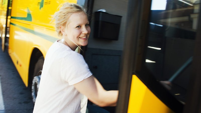 En kvinna som ler kliver på en buss.