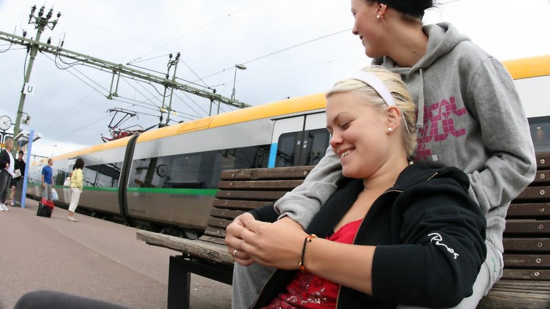 Två personer på en perrong med tåg i bakgrunden.