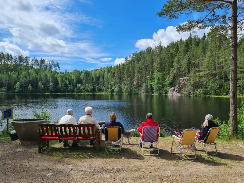 Äldre personer sitter på stolar och tittar ut över en sjö.