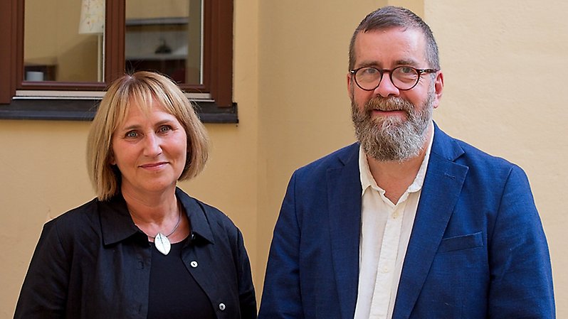 En man och en kvinna står bredvid varandra och tittar in i kameran.