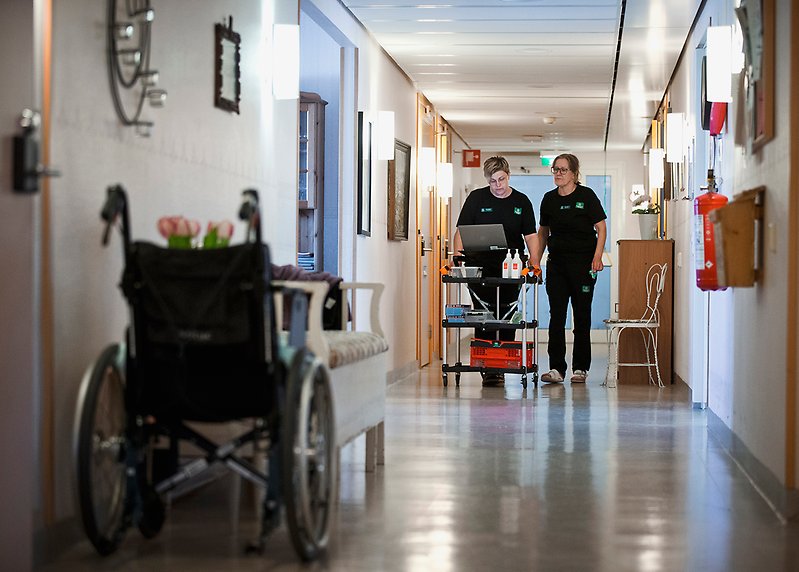 Mimmi och Tina går i en korridor på ett äldre- och gruppboende