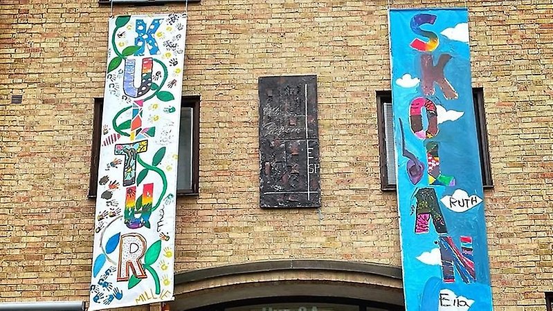 Två färgglada banderoller på en vägg, på en står det kultur och på andra skolan