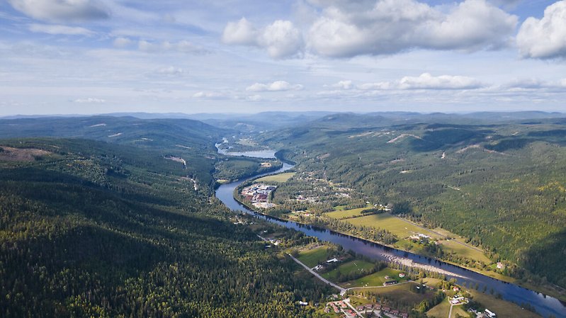 Klarälven slingrar sig fram längs dalen. På båda sidor som älven reser sig bergen.