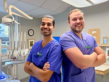 Oscar och William står sida vid sida med armarna i kors och ler i behandlingsrummet